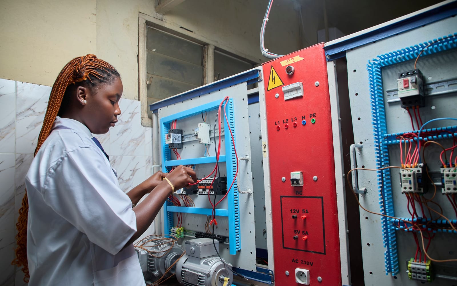 An engineer probing a wiring cabinet to trace a fault through a control system