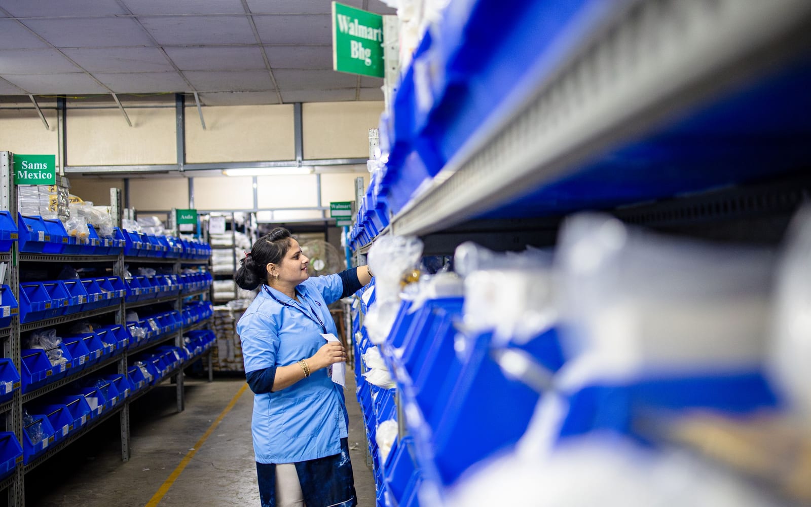A worker selecting parts from rows of labelled storage bins