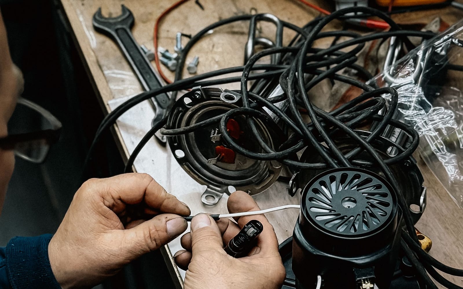 Hands working through a knot of cabling and components at a bench