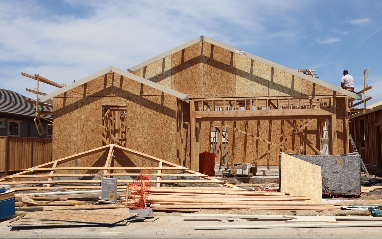 A timber-framed house under construction with roof trusses being fitted by hand