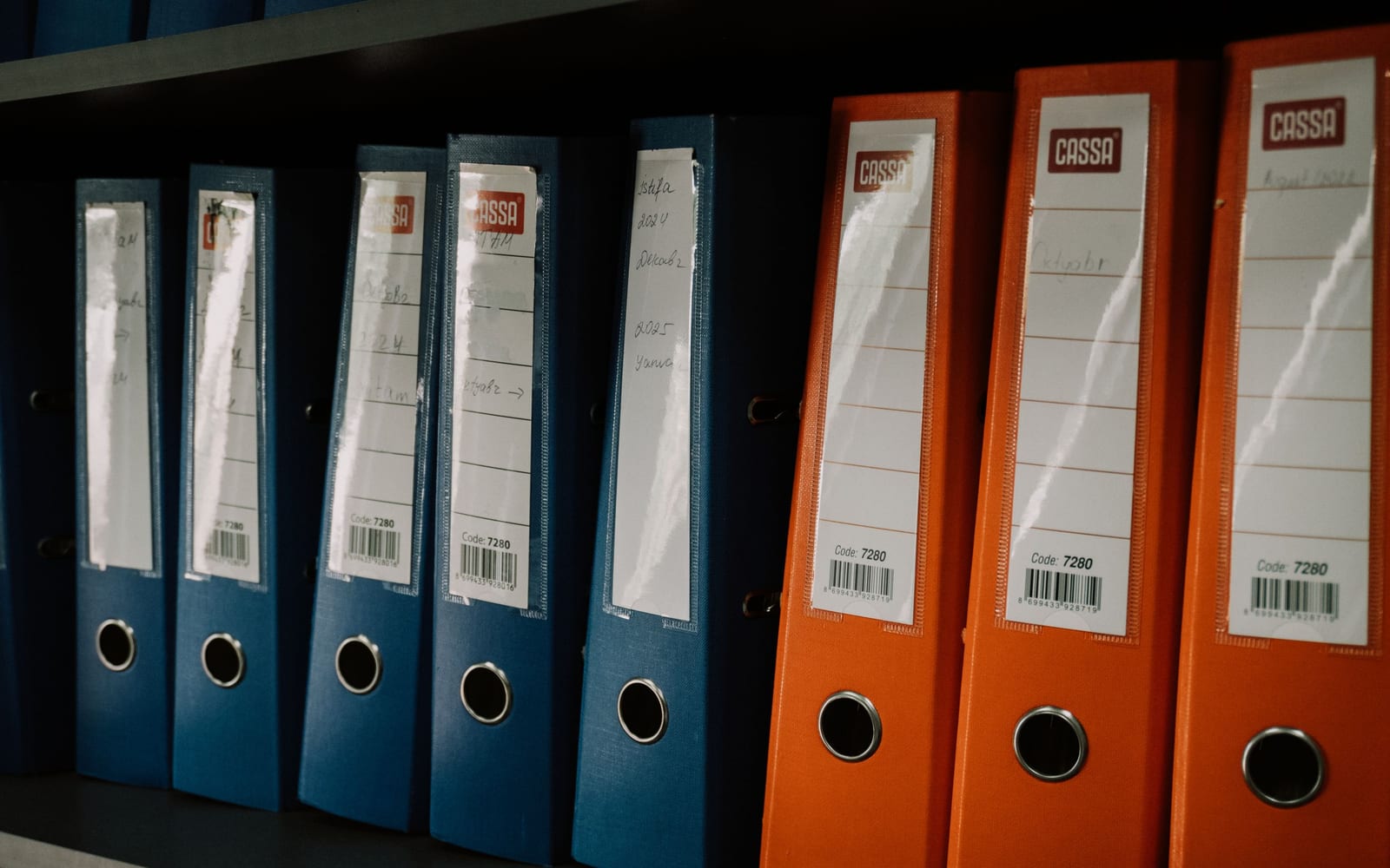 A shelf of archive box files with printed spine labels