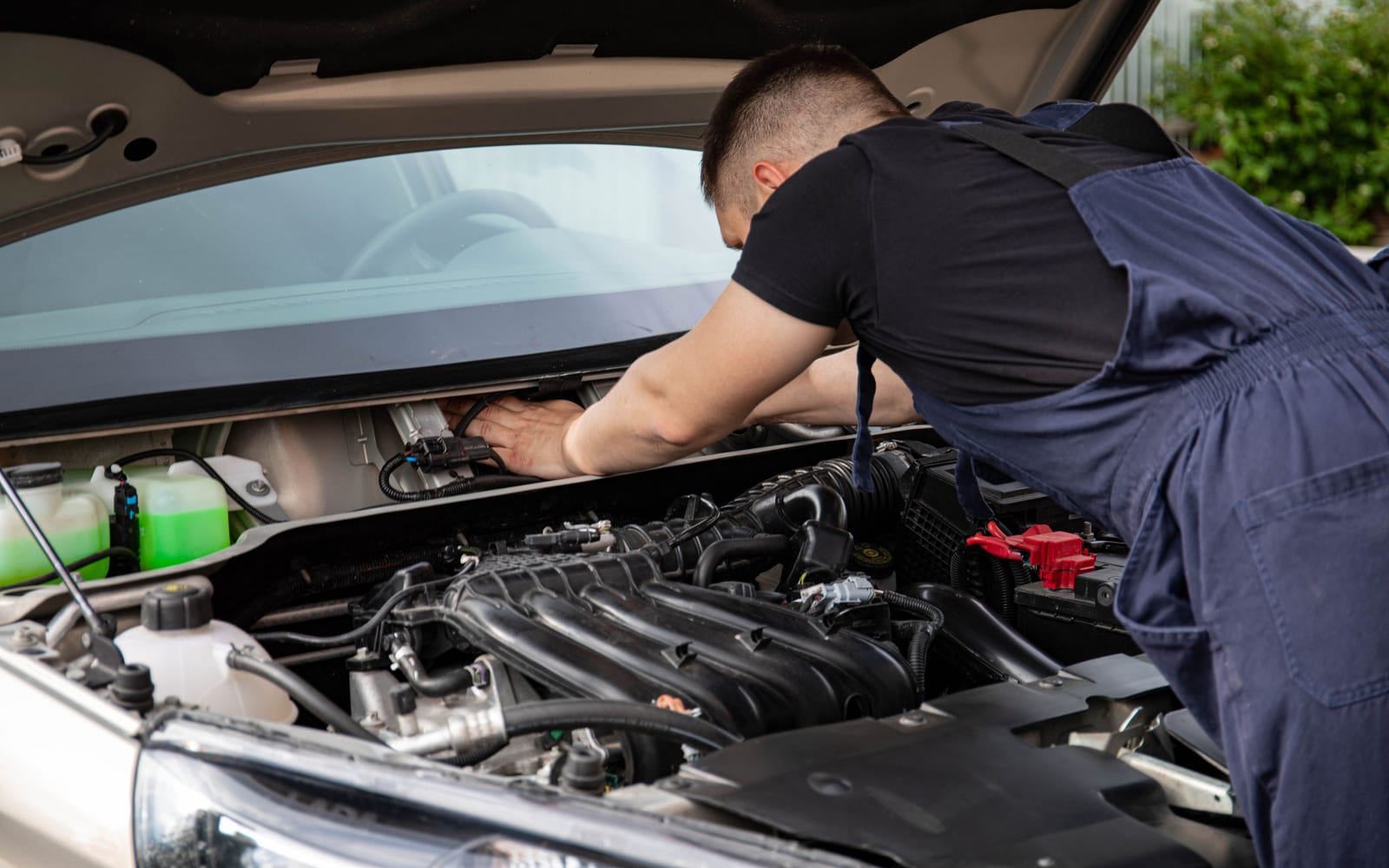 A mechanic leaning into an engine bay to diagnose a fault rather than guess at it