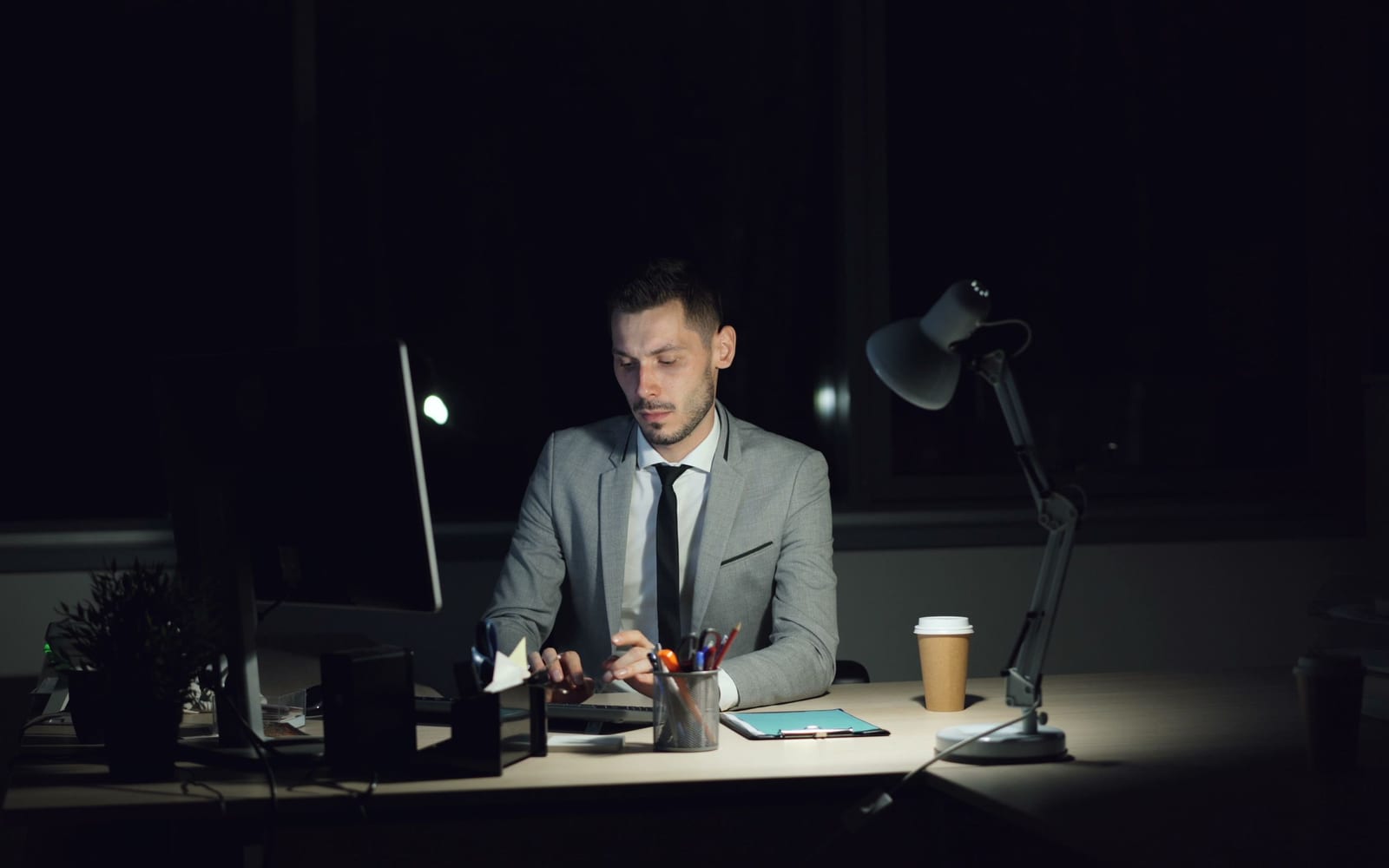 One person working alone at a desk late at night, lit by a single lamp