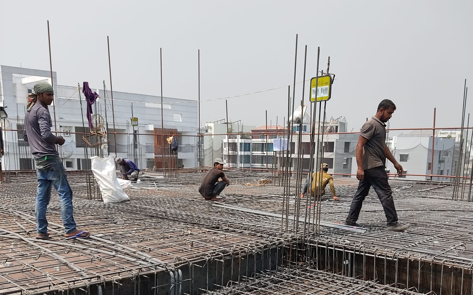Workers laying steel reinforcement across a slab before the concrete pour