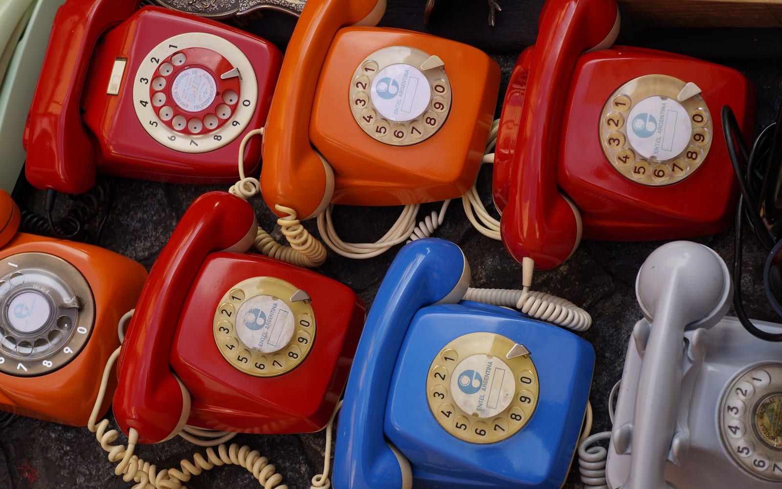 A wall of rotary telephones in different colours, all doing the same job