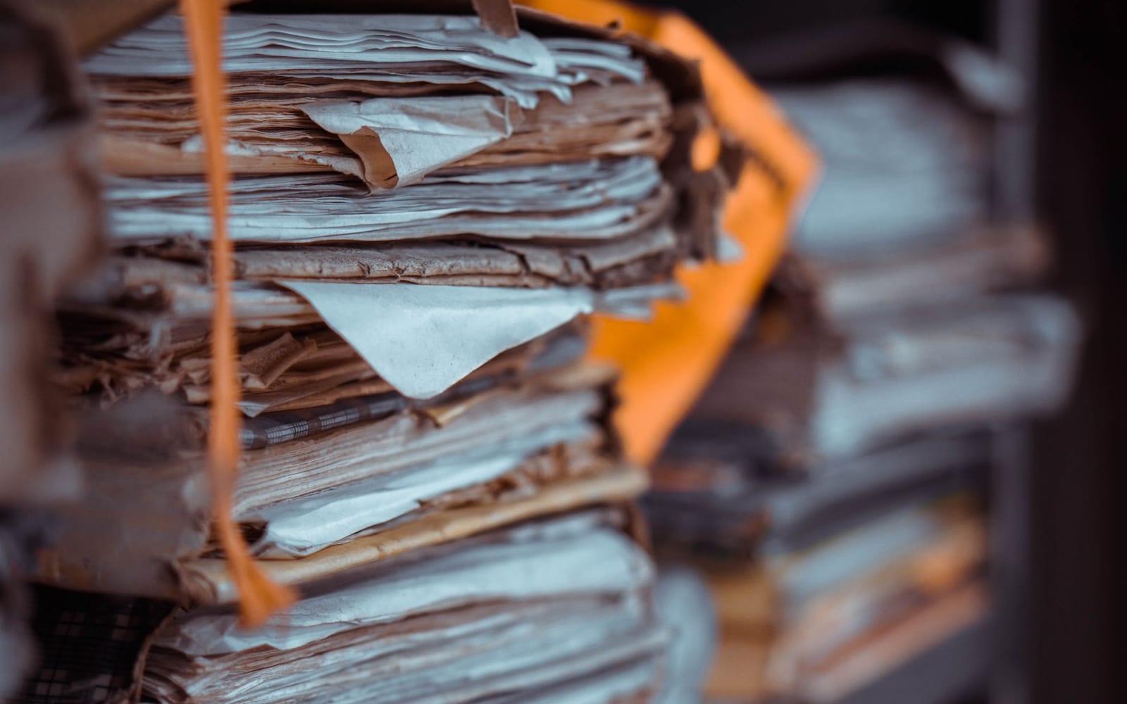 Stacks of old paper files tied with string, edges worn from years in storage