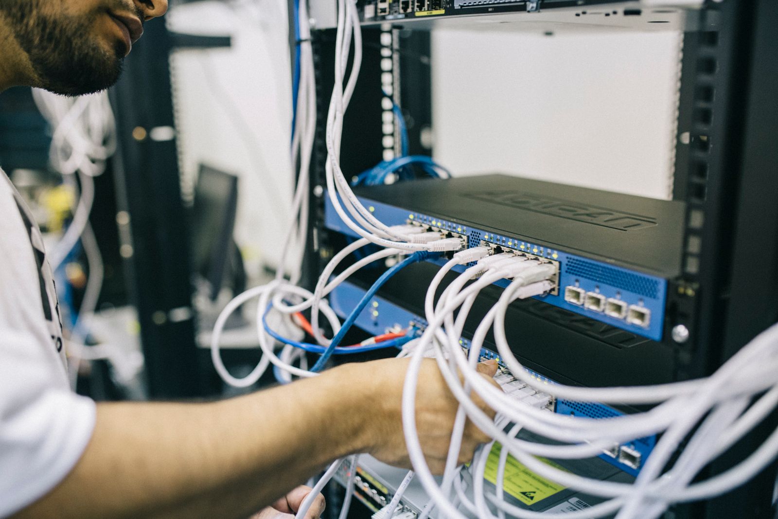 Network technician terminating ethernet in a live rack, the install and repair reality workshops must respect.
