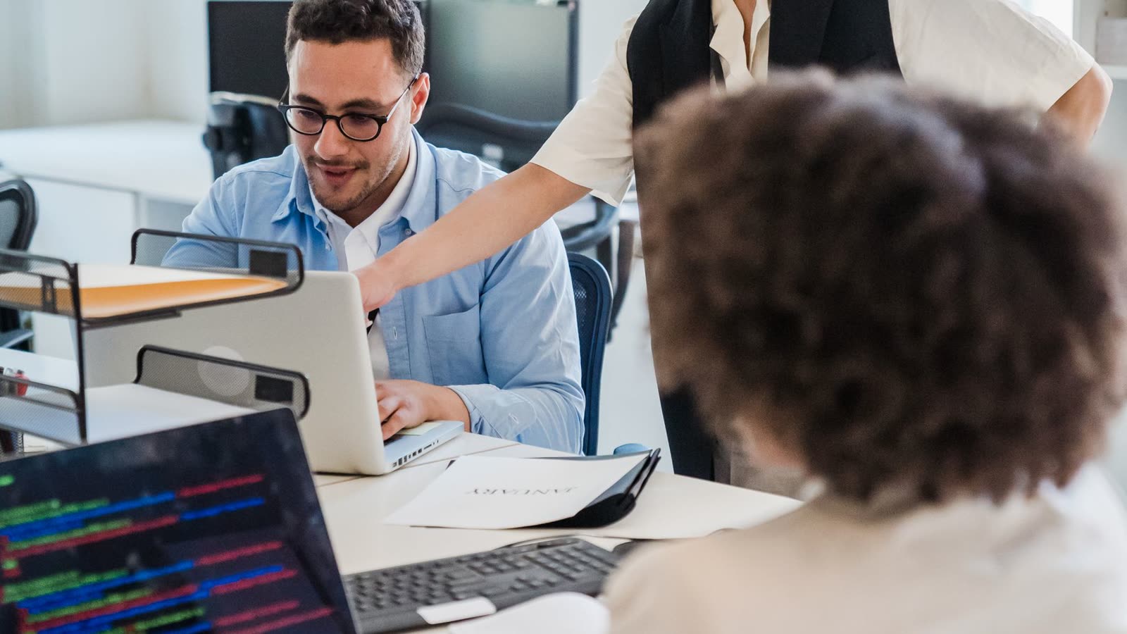 Three colleagues working through a technical decision together at a desk.