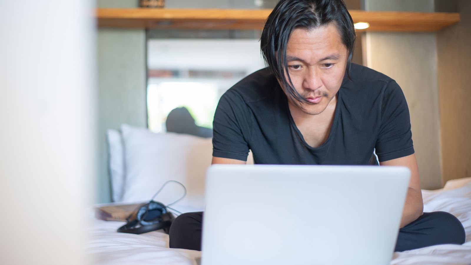 An analyst checking a printed chart against a dashboard on a laptop.