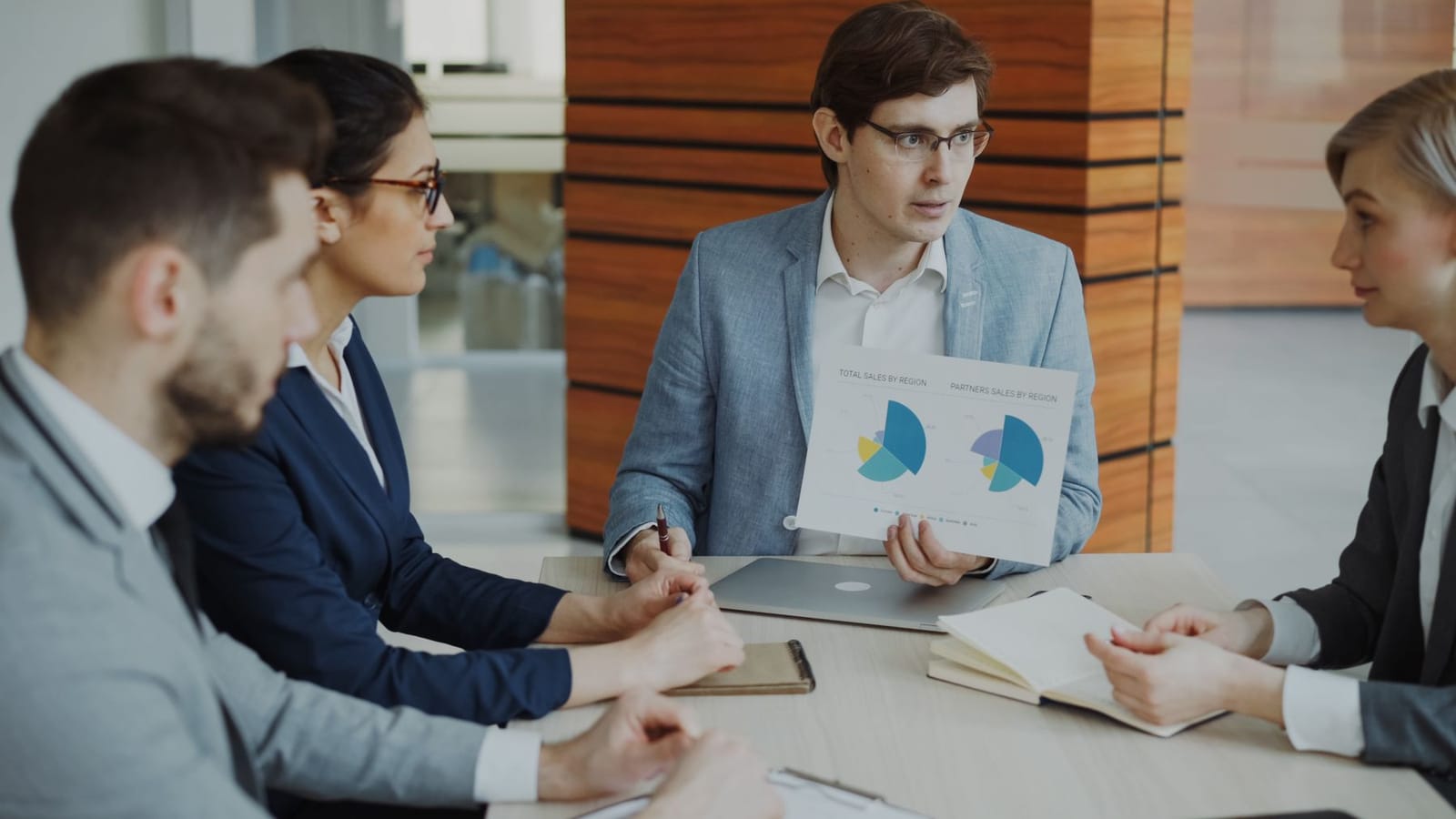 A sales team reviewing regional sales charts together in a meeting room.
