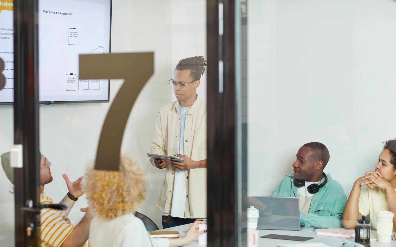 An enterprise meeting in a glass-walled conference room.