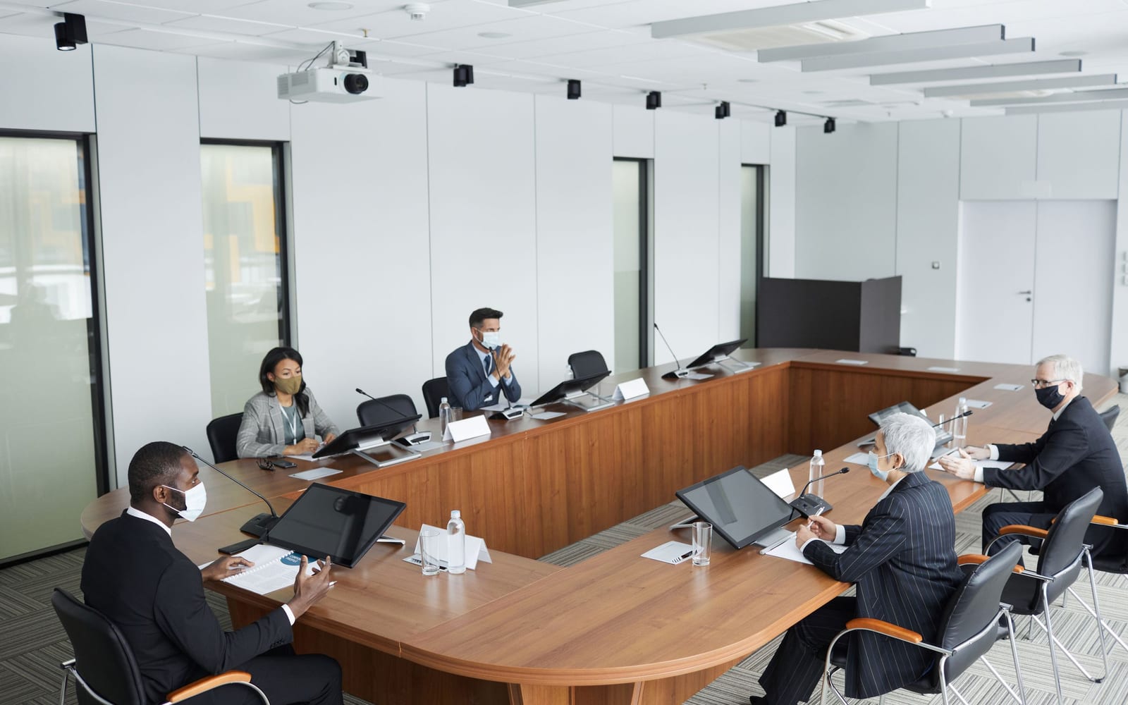 An enterprise meeting in a glass-walled conference room.