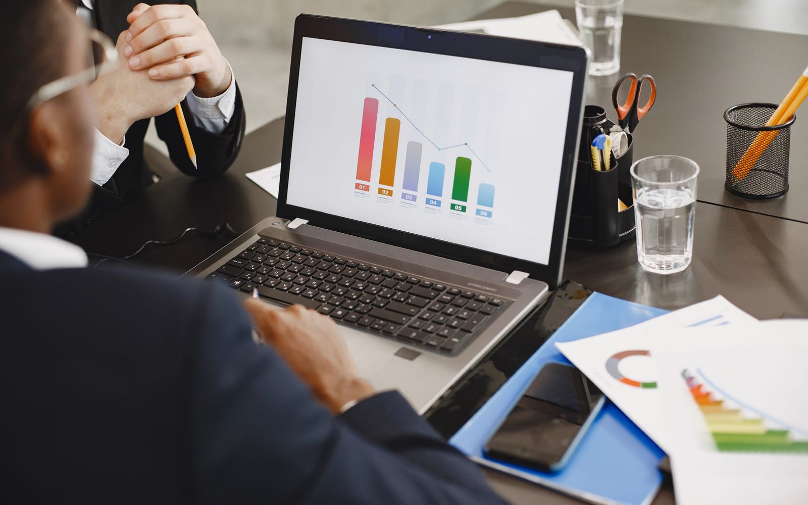 An analyst reviewing figures on a laptop in an office.