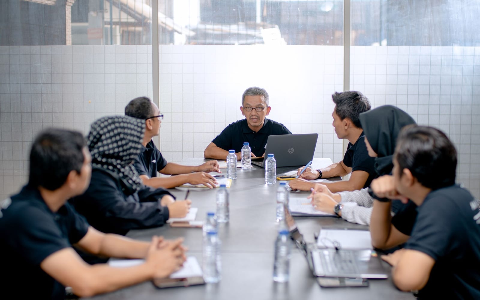 An enterprise meeting in a glass-walled conference room.